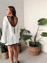 Vestido corto tejido al crochet color blanco, con mangas largas y escote redondo con borde negro.
