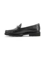 Mocasín de cuero negro con detalle de hebilla metálica plateada.