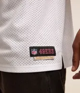 Remera deportiva blanca de manga corta con tecnología Dry, cuello en V, detalles de rayas en mangas y cuello, y estampado del logo de los San Francisco 49ers.