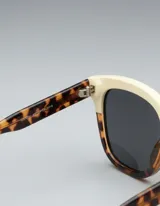 Lentes de sol cuadrados con armazón bicolor: parte superior color crema y parte inferior con estampado carey. Lentes polarizados negros con protección UV400.