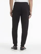 Pantalón de jogging negro de algodón con cintura elástica ajustable con cordón, bolsillos laterales, puños elásticos y logo de Calvin Klein bordado en la pierna.