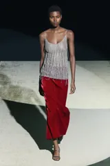 Falda midi de terciopelo color borgoña, de tiro alto y corte recto. Tiene una abertura en la parte trasera y cierre de cremallera oculta en la costura.