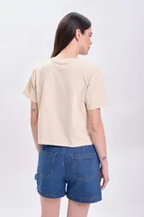 Remera color crema de corte cropped, con mangas cortas y estampa frontal con la frase "Rock and Roll" y un rayo alado. 