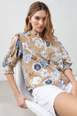 Camisa de manga 3/4 abullonada con puño elastizado, cuello mao y estampado floral en tonos azules y blancos sobre fondo tostado.