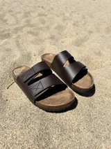 Sandalias marrones con doble tira en el empeine, plantilla de corcho y suela de goma.