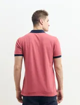 Remera polo blanca de piqué con cuello y puños en azul marino. Tiene tapeta de dos botones y bolsillo de parche en el pecho.