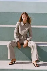 Pantalón de tiro bajo color beige, con bolsillos delanteros y falsos bolsillos de vivo en la espalda. Piernas rectas y cierre frontal con cremallera, botón interior y ganchos.