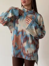 Sweater de cuello alto con estampado abstracto en tonos celeste, marrón y blanco.