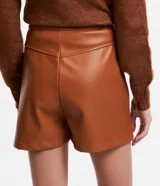 Short corto de cuero sintético color marrón, con cintura alta, bolsillos laterales con solapa y cierre frontal con botón y cremallera.