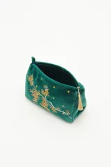 Bolso de mano tipo clutch, color verde esmeralda, de terciopelo con bordado de flores amarillas y blancas. Incluye un cierre superior y un colgante de borla dorada.