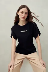Remera negra de manga corta con bordado frontal "C’est la vie", calce relajado y frunces laterales.