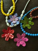 Collar corto de cuentas celestes con dije de flor fucsia.