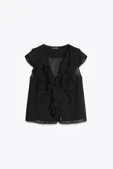 Blusa negra sin mangas con escote en pico y volantes. Cierre frontal con botones y lazo fino con apliques dorados.