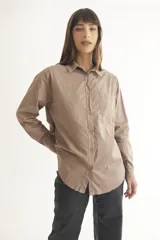 Camisa color beige de corte clásico con cuello, mangas largas y bolsillo frontal.