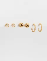 Set de tres pares de aros dorados con cierre a presión. Incluye un par de aros tipo botón con detalle de strass, un par de aros tipo botón con diseño de nudo y un par de aros tipo argolla texturizada.