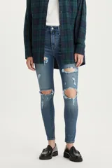 Jean skinny de tiro alto color azul denim con roturas grandes en ambas rodillas y pequeños detalles de roturas en los muslos.