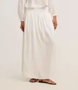 Pollera evasé midi color blanco, confeccionada en viscolino con 30% de lino, con lastex en la parte trasera de la cintura y forro interno.