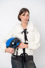 Cardigan blanco de lana con cuello de piel sintética, cierre frontal con lazos de terciopelo negro y corte holgado.