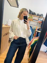 Camisa blanca oversize con detalles de puntilla en el frente y mangas abullonadas.