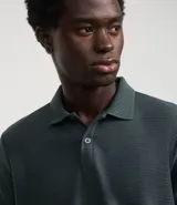 Camisa polo de hombre color verde oscuro, de corte regular, manga corta y cuello con botones.