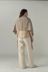 Chal de lana fina sin teñir, con calce en hombros, abrochadura con alamar de fieltro, bolsillos de cuero y terminación con flecos. Diseño exclusivo de Don Baez, hecho en Uruguay.