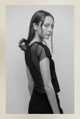 Camiseta negra de corte ajustado, con mangas cortas y espalda de tul transparente. Diseño versátil que permite usarla tanto de frente como de espalda.