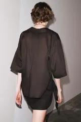 Camisa marrón de corte recto, con cuello solapa, manga corta y cierre frontal con botones.