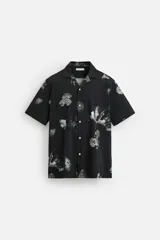 Camisa negra con estampado floral en tonos grises, de manga corta y cuello bowling.