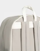 Mochila gris claro de tela deportiva con correas regulables, manija superior, cierre superior, bolsillo central con cierre y puller de cordón y goma, bolsillo frontal con cierre y puller de cordón y goma, y bolsillos laterales.