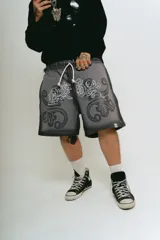 Bermuda de felpa gris oscuro con lavado gastado, corte ancho, estampado con serigrafía premium y bordado a un color.