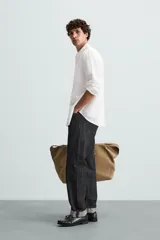 Camisa celeste a rayas verticales, de corte relaxed fit, confeccionada en lino y algodón. Tiene cuello abotonado, manga larga con puños abotonados, bolsillo de parche en el pecho y cierre frontal con botones.