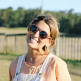 Lentes de sol redondos con marco de madera color marrón claro y lentes grises.