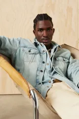 Campera de jean celeste claro, con cuello clásico, cierre frontal con botones metálicos y bolsillos con solapa abotonada en el pecho.