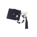Llavero pulsera con tarjetero negro texturado con broche dorado, cuentas en tonos neutros (blanco, gris y negro) y fleco a juego.
