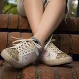 Zapatilla de cuero vacuno con detalles en charol rosa y azul claro, y brillos dorados en la puntera.