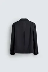 Blazer negro de corte relaxed fit confeccionada en tejido con lana. Cuello con solapas de muesca y manga larga acabada en puño con botones. Bolsillos de vivo en pecho y de solapa en cadera. Detalle de bolsillo interior. Bajo con aberturas en espalda. Cierre frontal de botonadura.