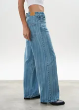 Pantalón de jean celeste con rayas verticales, tiro bajo y corte wide leg.