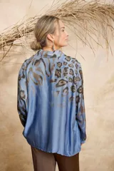 Camisa celeste con estampado animal print en tonos marrones, de seda, con cuello camisero, cierre frontal con botones y mangas 3/4.