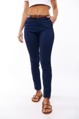 Pantalón azul marino de corte skinny, con bolsillos laterales y traseros. Se ajusta a la cintura con cinturón de cuero marrón.