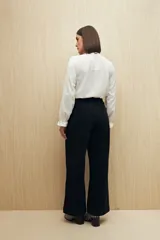 Pantalón de vestir color beige, de corte wide leg y tiro alto, con bolsillos laterales y traseros.