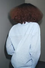 Camisa oversize celeste con textura de algodón, cuello solapa y manga larga. Presenta pliegues delanteros y bajo asimétrico.