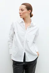 Camisa blanca con detalles de strass y perlas, de corte clásico y manga larga.