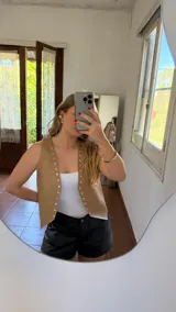 Chaleco marrón de ecocuero con tachas plateadas.