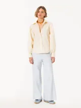 Camisa amarilla confeccionada en poplin rayado con hilos de lurex, mangas abullonadas, botones visibles forrados a tono de tela y detalles de remache Lipstick en la punta del cuello.