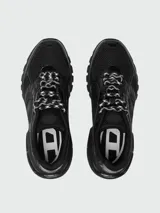 Zapatillas deportivas Diesel modelo S-Pro-V-Dense, color negro, con diseño robusto y estilo 'chunky' o 'dad shoe'. Presentan una combinación de malla transpirable y superposiciones de material sintético brillante. Los cordones son bicolores (negro y blanco).
