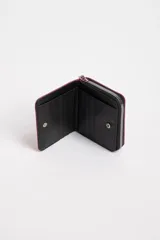 Billetera cuadrada color fucsia con cierre de cremallera y tirador con diseño de zigzag. Tiene un parche circular con borde dorado y un corazón rosa en el centro.
