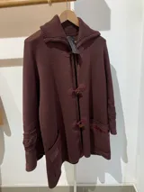 Saco capa tejido en lana color bordo, con cuello alto y cierre con broches tipo duffle-coat.