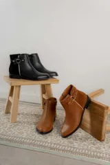 Bota corta negra de cuero con detalle de hebilla metálica y elástico en el tobillo.