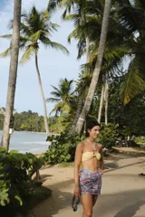 Pareo rectangular con estampado a cuadros en tonos celeste, naranja y blanco, con detalle de flecos en los bordes.