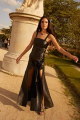 Vestido negro de cuero con tirantes anchos y escote recto. Presenta un detalle de costura decorativa con cordón azul oscuro a la altura de la cintura.